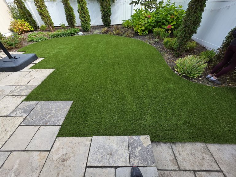 Curved residential artificial grass lawn integrated with paver walkway