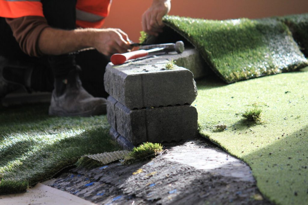 Cutting artificial turf seam against concrete edge during installation