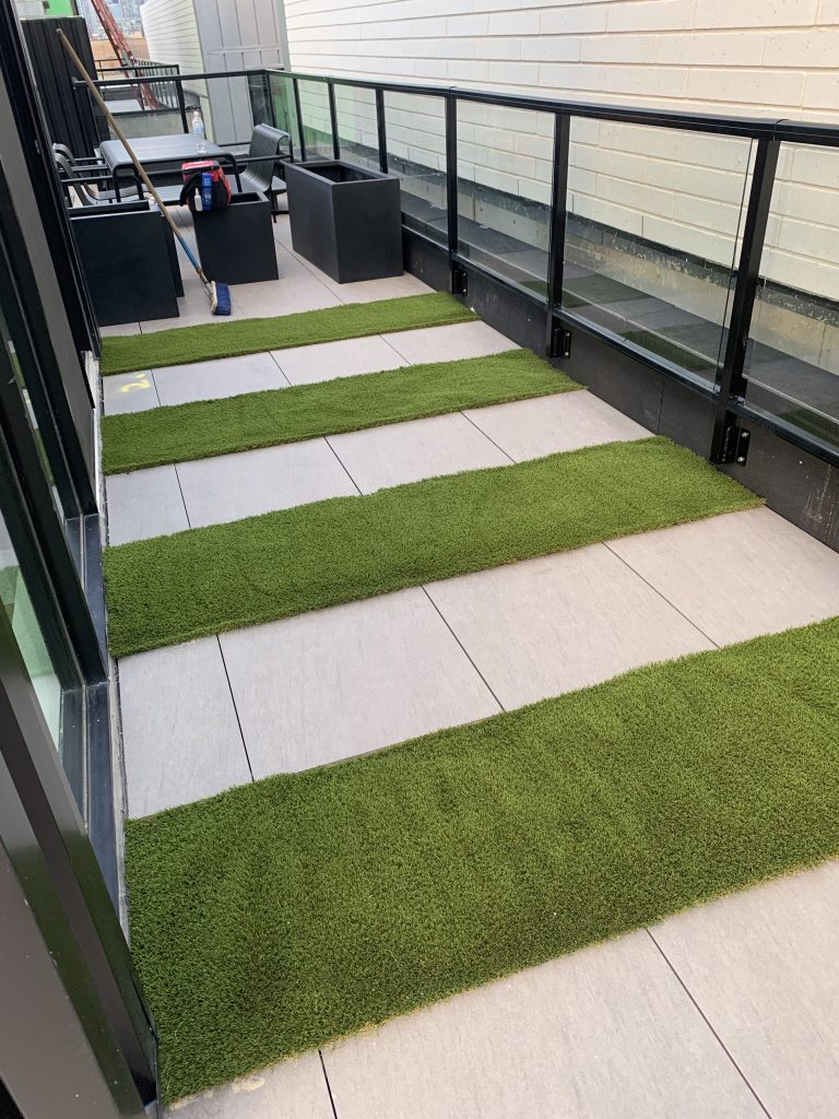 Concrete walkway with artificial grass strips installed between pavers